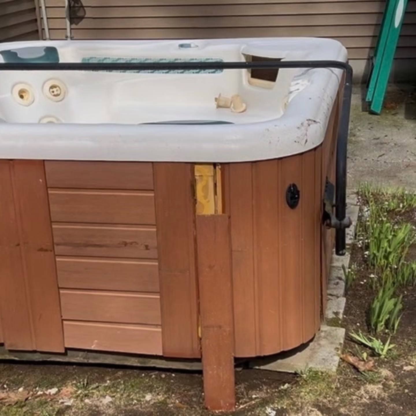 Old wood-sided hot tub on a patio before removal